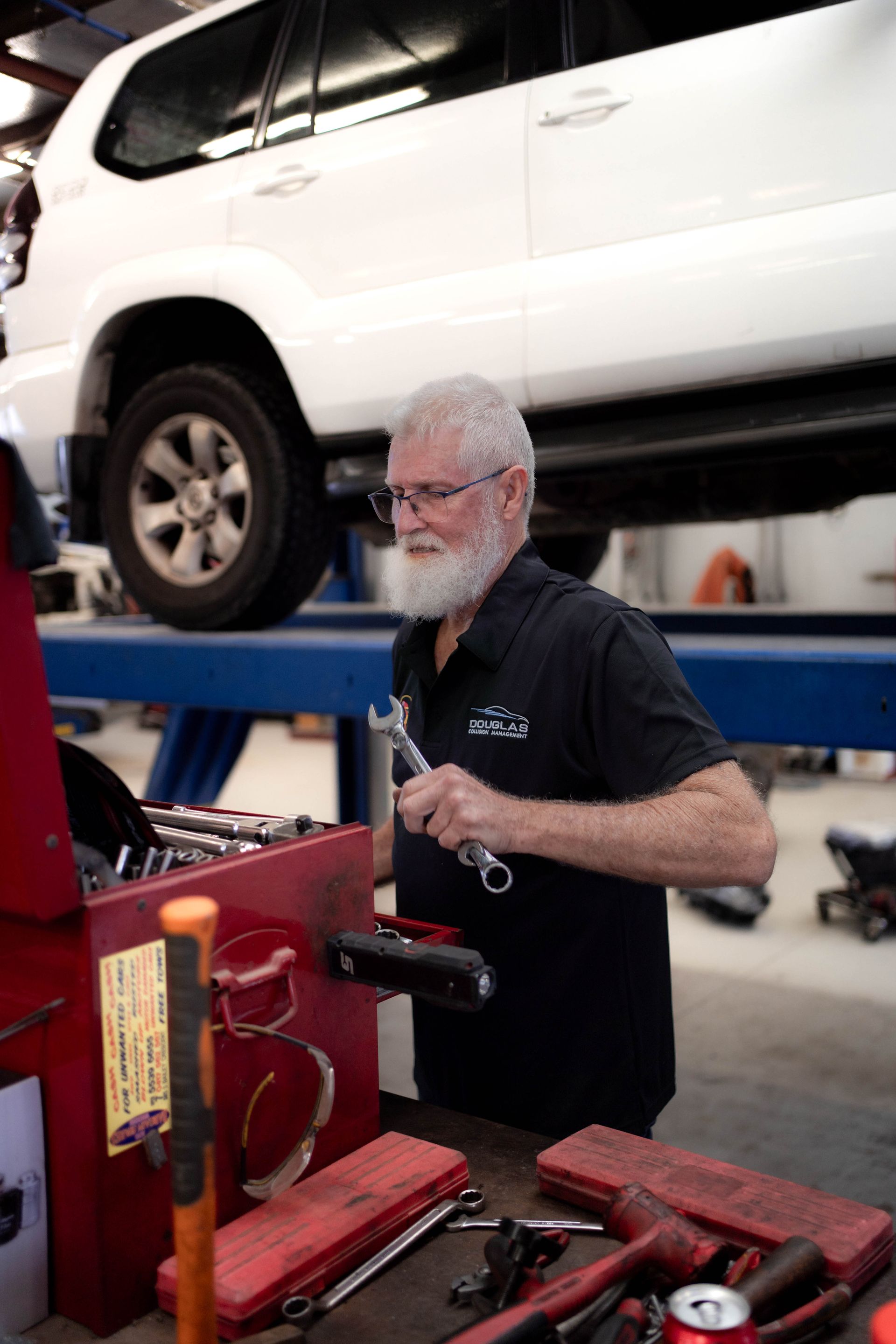 Sam the mechanic working on a white 4x4 on a hoist— Douglas Collision Management In Currajong, QLD