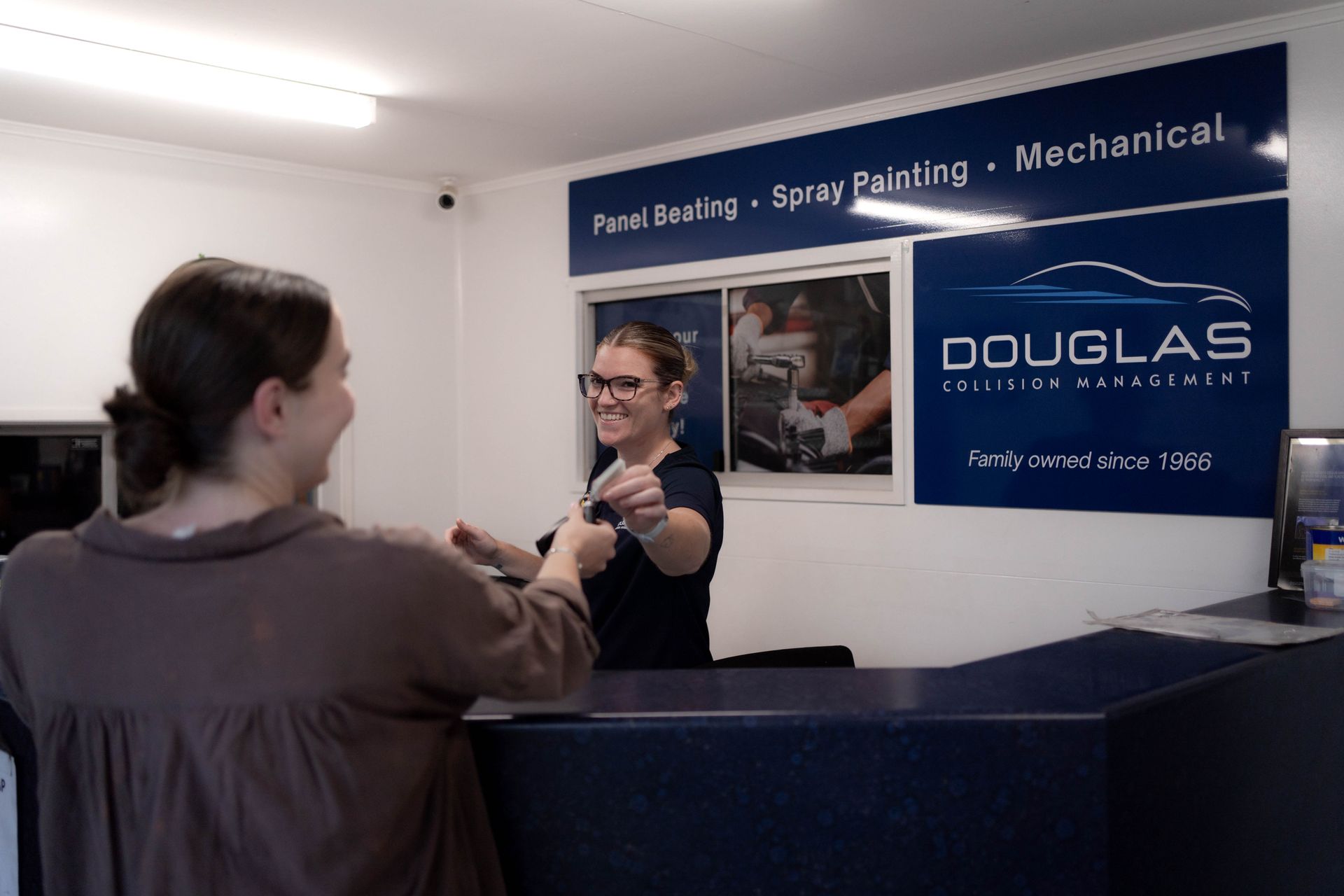 Woman receiving keys from employee at a car repair shop's front desk — Douglas Collision Management In Currajong, QLD