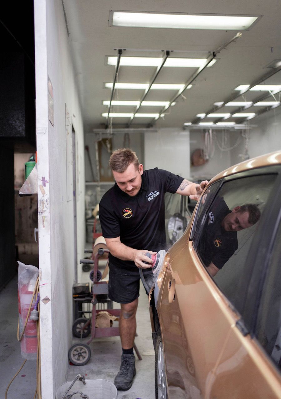 Man sanding the side of a gold car in an auto body shop — Douglas Collision Management In Currajong, QLD