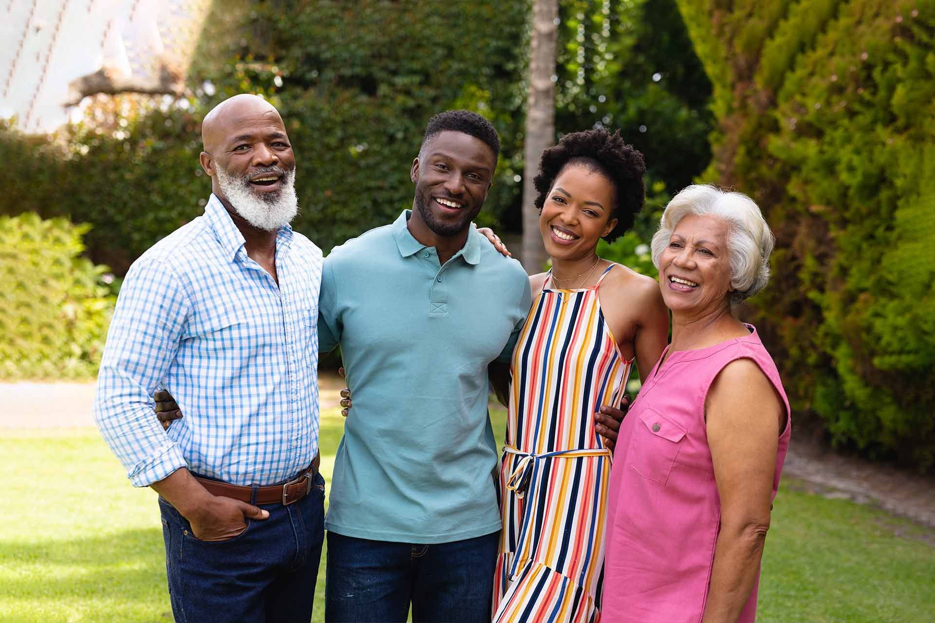 Family of four smiling, posing outdoors in a garden setting.