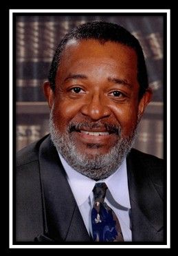 A man with a beard is wearing a suit and tie and smiling.