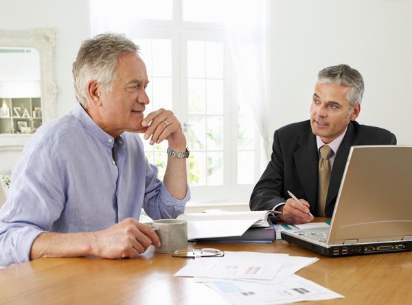Two men are sitting at a table with a laptop.