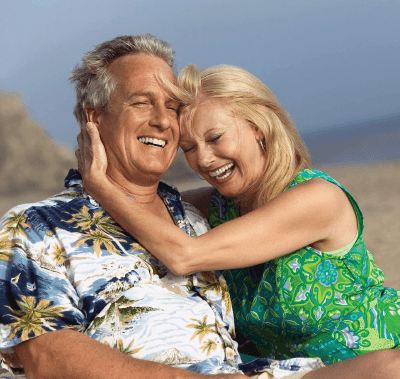 A woman is hugging a man on the beach