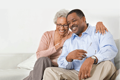 A man and a woman are sitting on a couch and smiling.