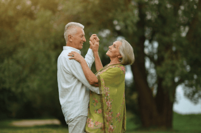 An elderly couple is dancing in a park.