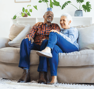An elderly couple is sitting in a wooden chair.