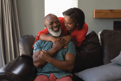 A woman is hugging a man while sitting on a couch.