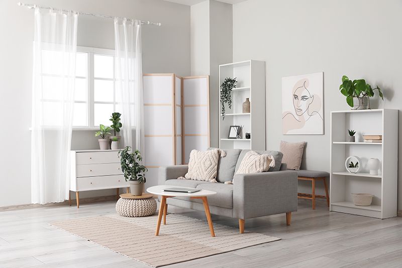 A living room with a couch , coffee table , shelves and curtains.