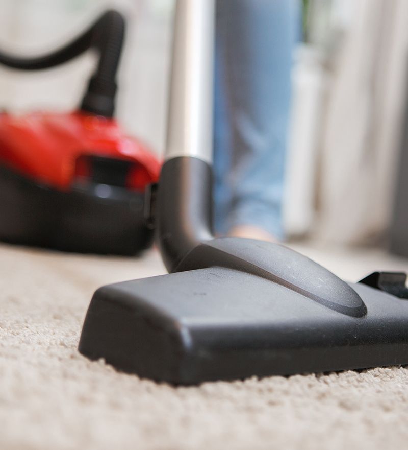 A person is using a vacuum cleaner on a carpet.