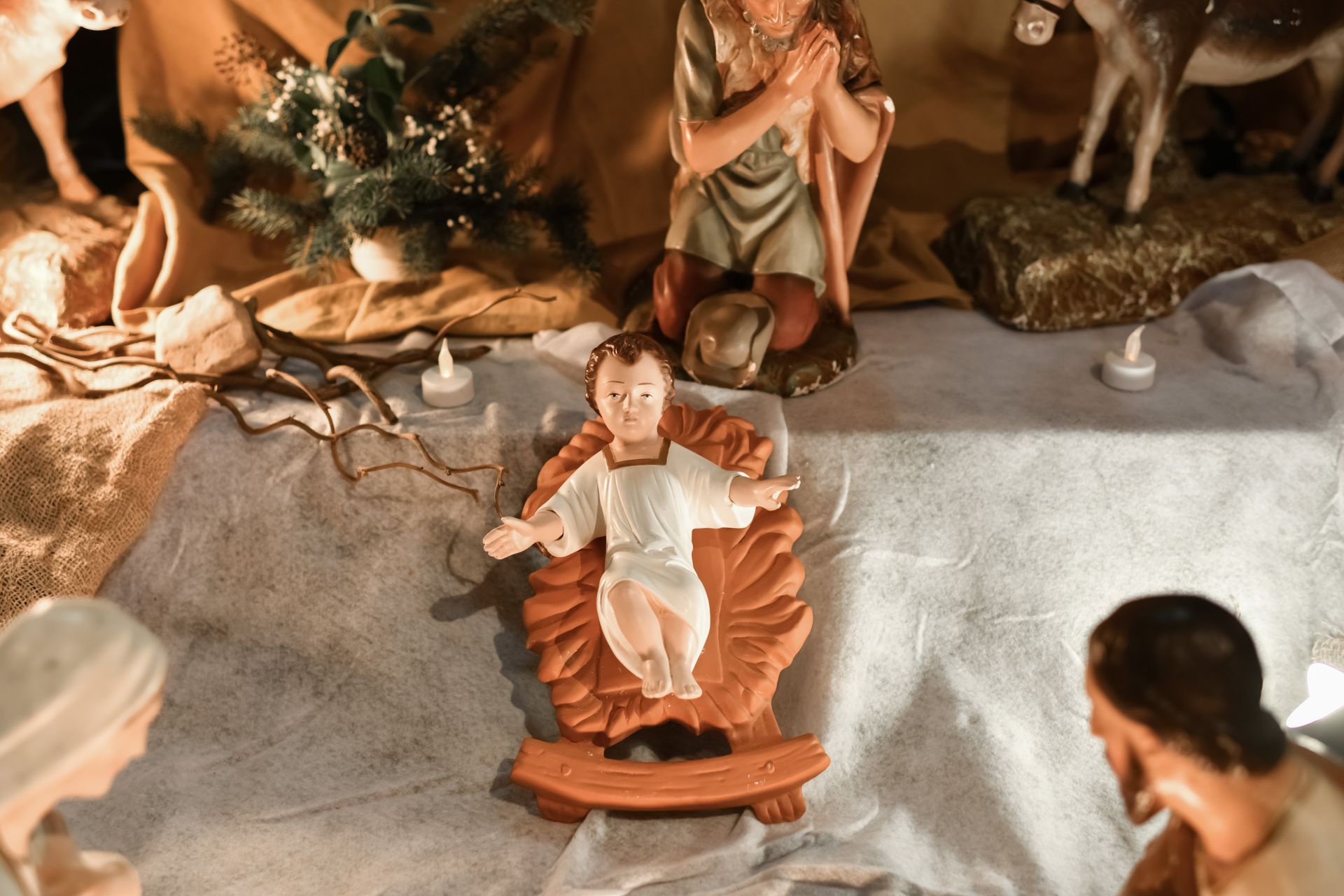 Representación de un pesebre navideño con el Niño Jesús, José y María, rodeados de decoración rústic