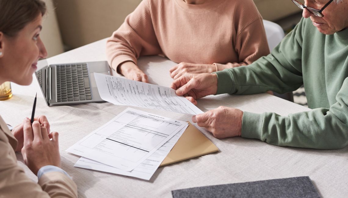 Manos adultas revisando una libreta y documentos para organizar decisiones familiares importantes.