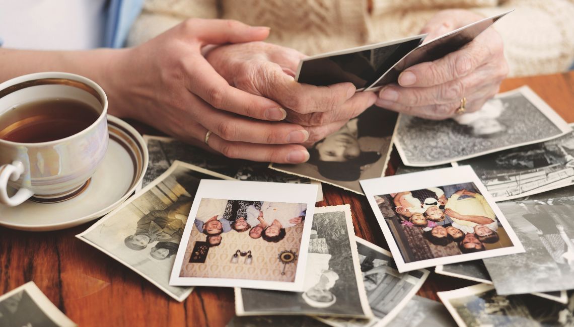 Recuerdo de varias generaciones a través de fotos familiares antiguas sostenidas por una persona may