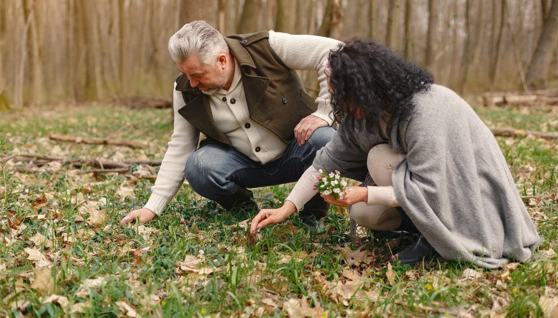 Hombre y mujer recogiendo plantas nativas para un memorial natural en un claro del bosque.