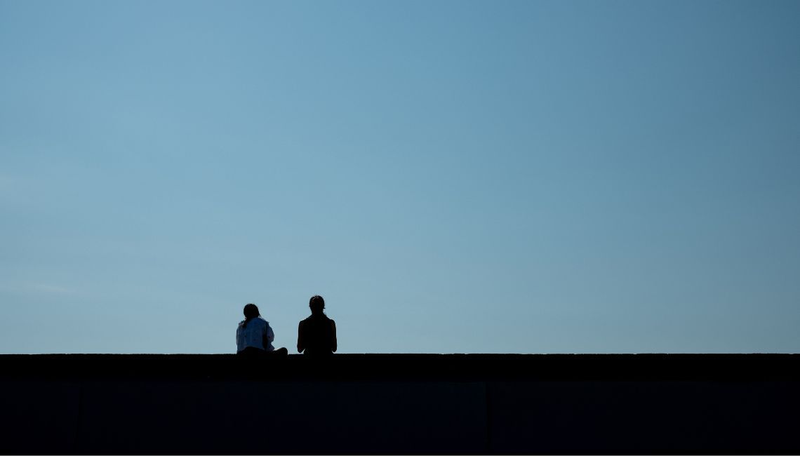Dos figuras en contraluz mirando al horizonte, con mucho espacio vacío; apoyo y alejamiento durante