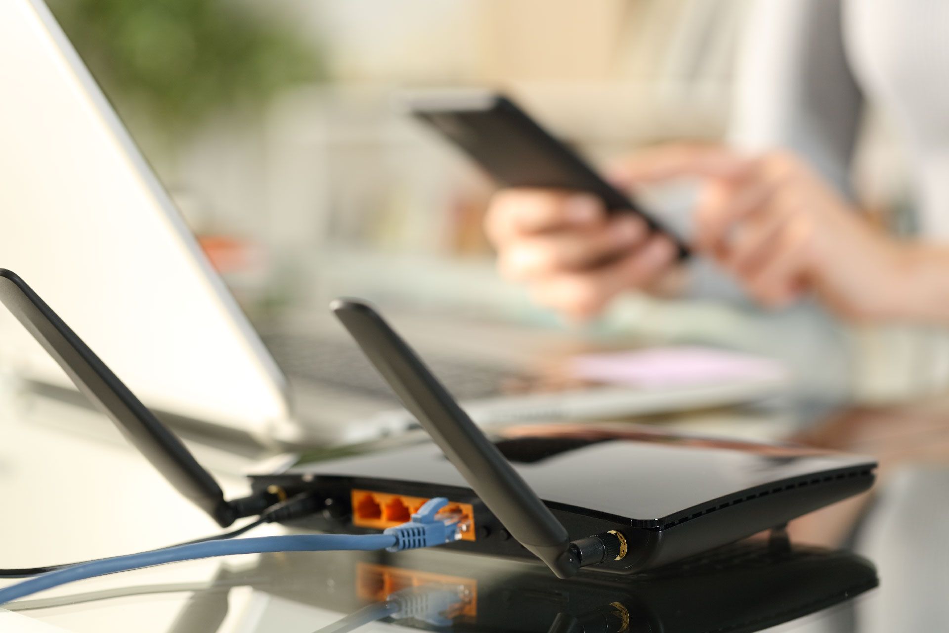 Una persona está usando un teléfono celular al lado de un enrutador.