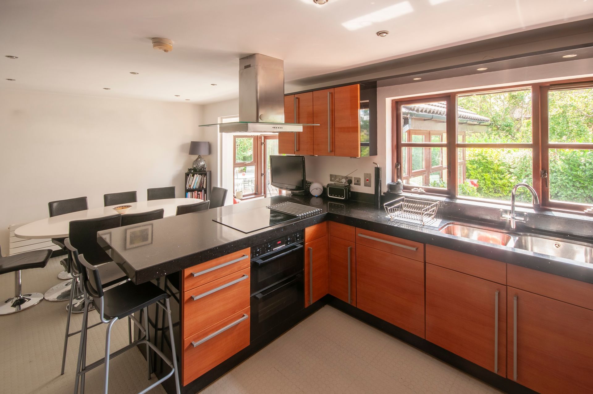 Modern kitchen with a black island, wooden cabinets, and a dining table.