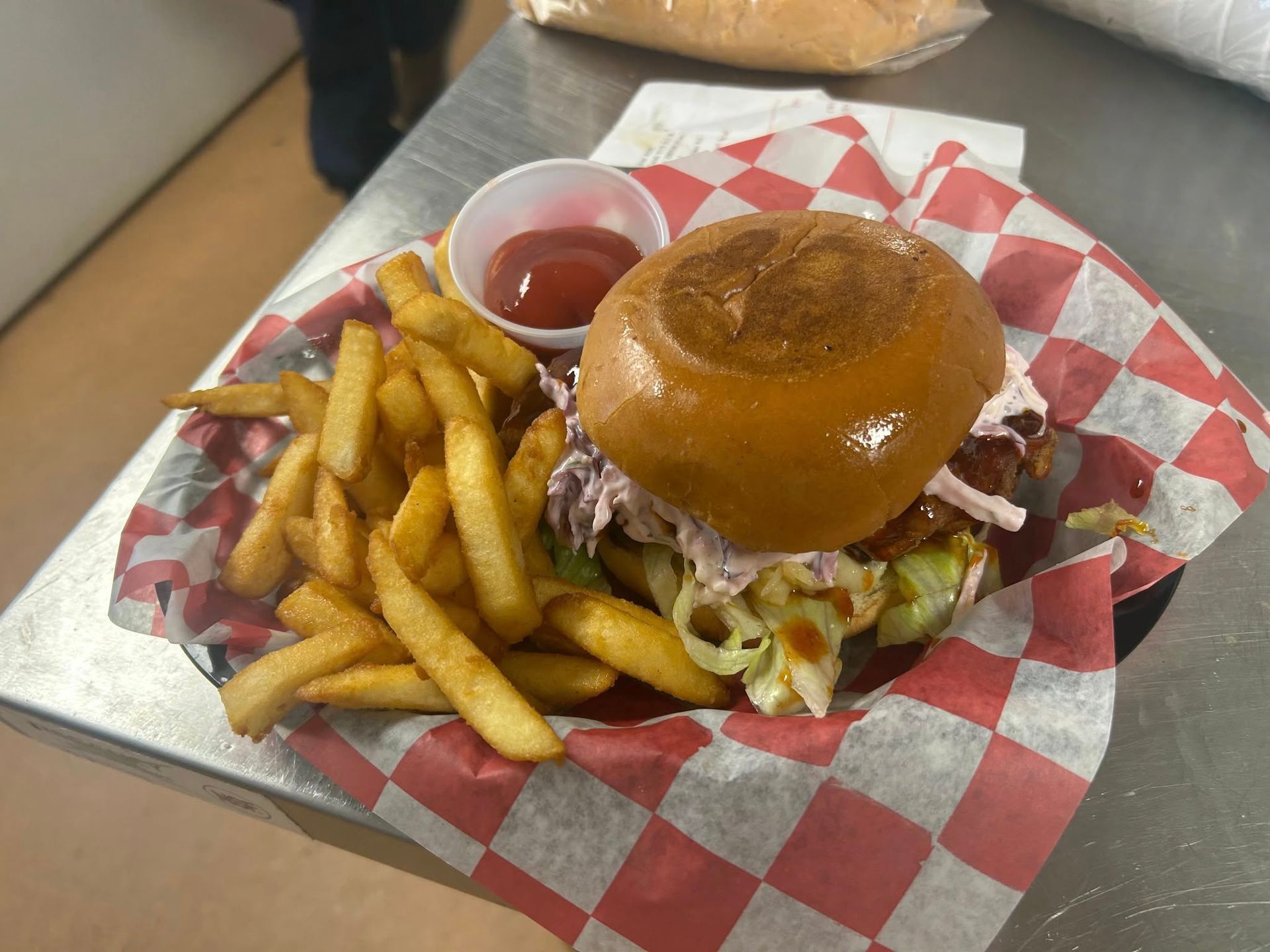 Burger and fries in a checkered basket, with ketchup.