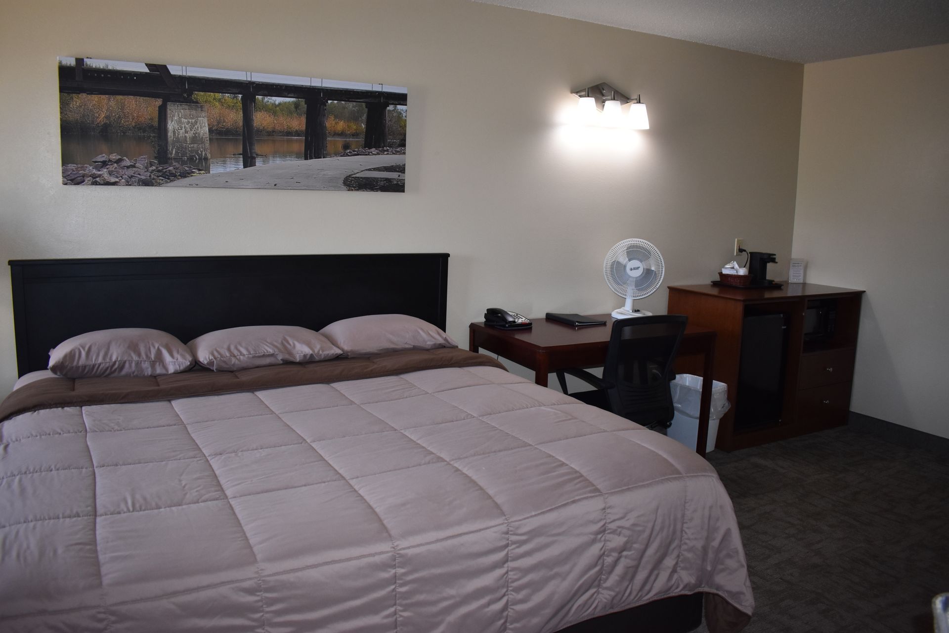A hotel room with a king size bed and a fan