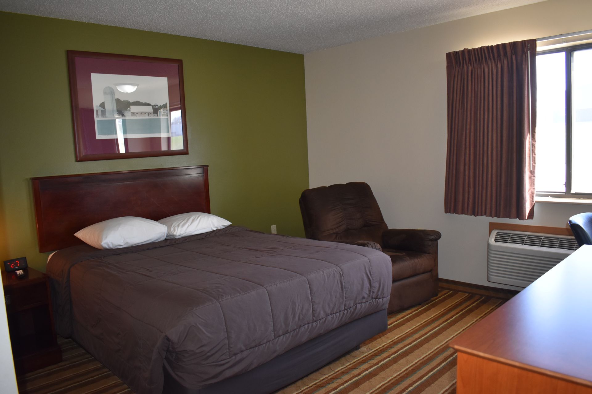 A hotel room with a king size bed and a chair