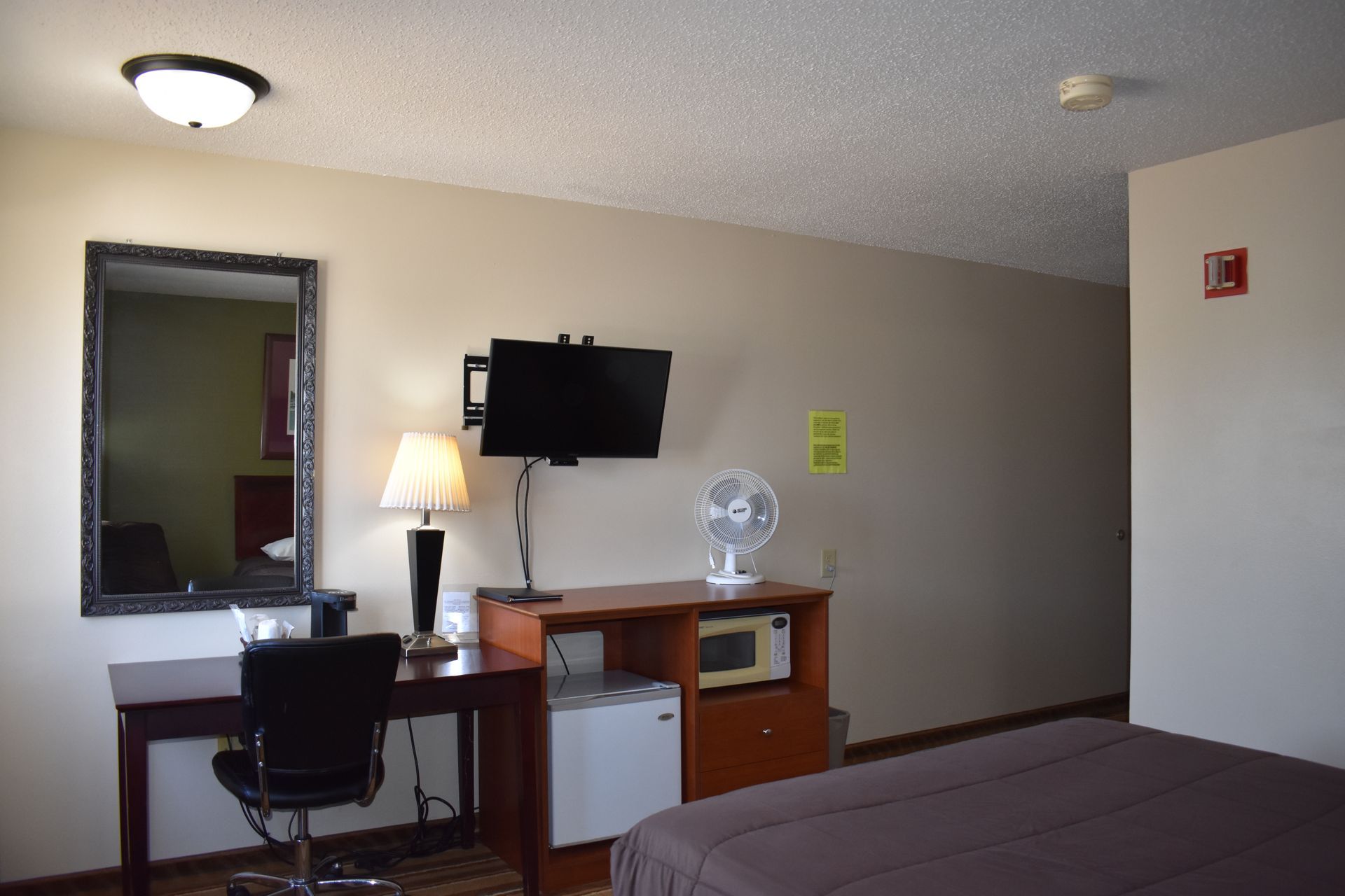 A hotel room with a bed a desk and a television