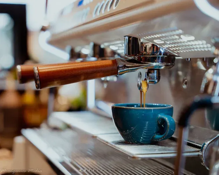 Two bowls of soup with a spoon and bread on a table.
