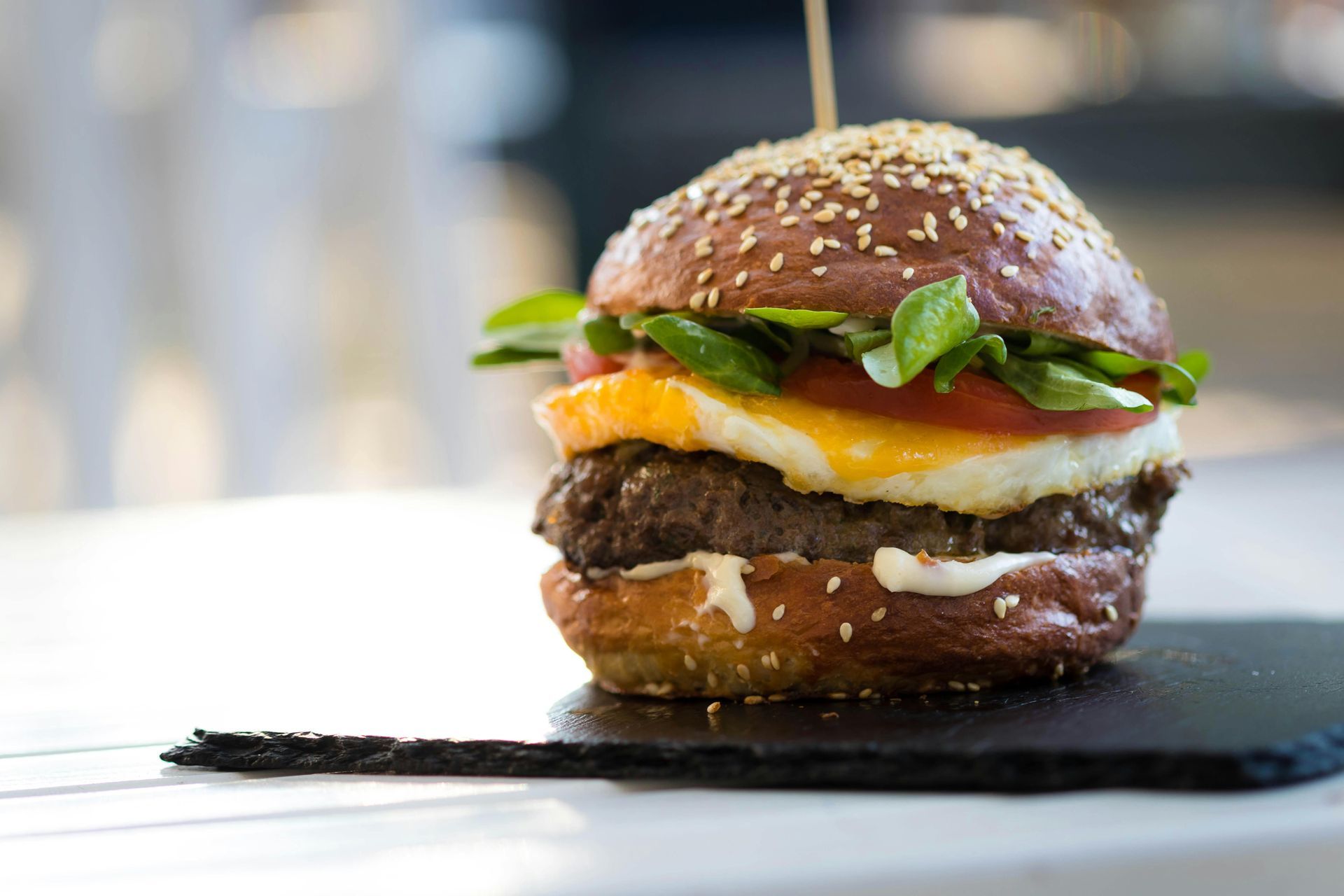 A close up of a hamburger on a cutting board on a table.