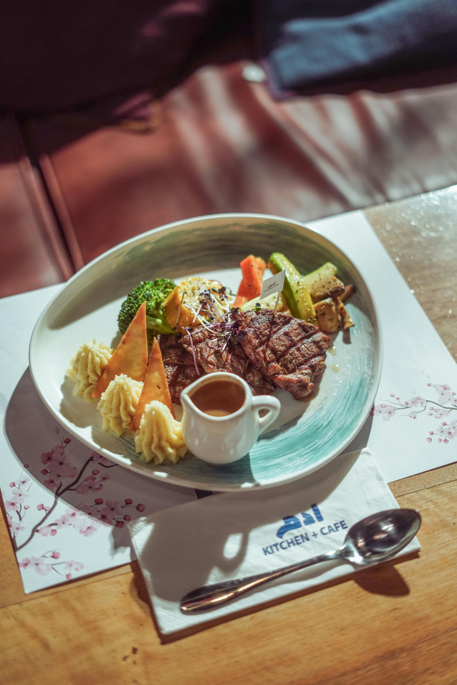 A plate of food with meat and vegetables on a table with a spoon.