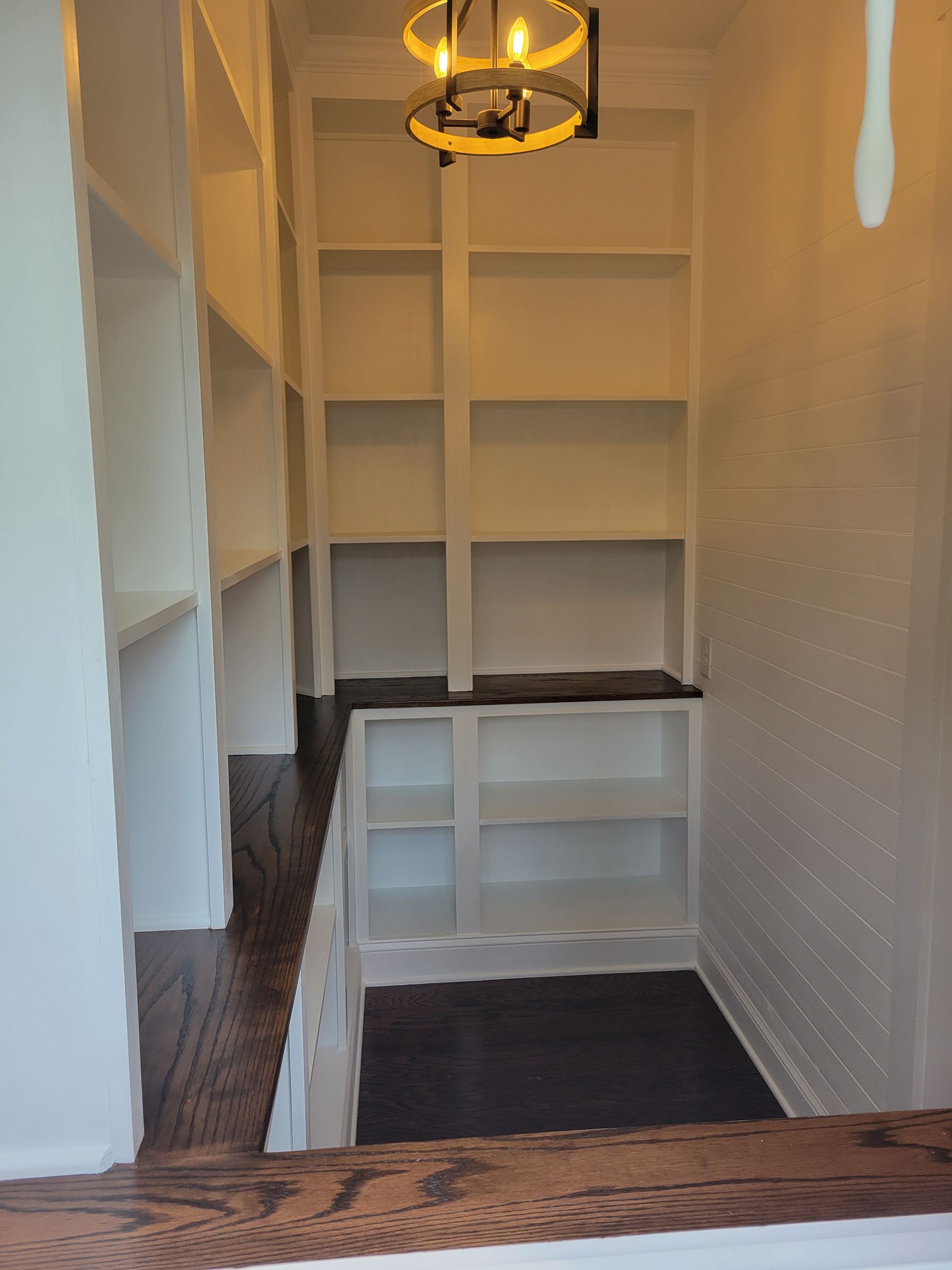A room with a lot of shelves and a chandelier hanging from the ceiling.