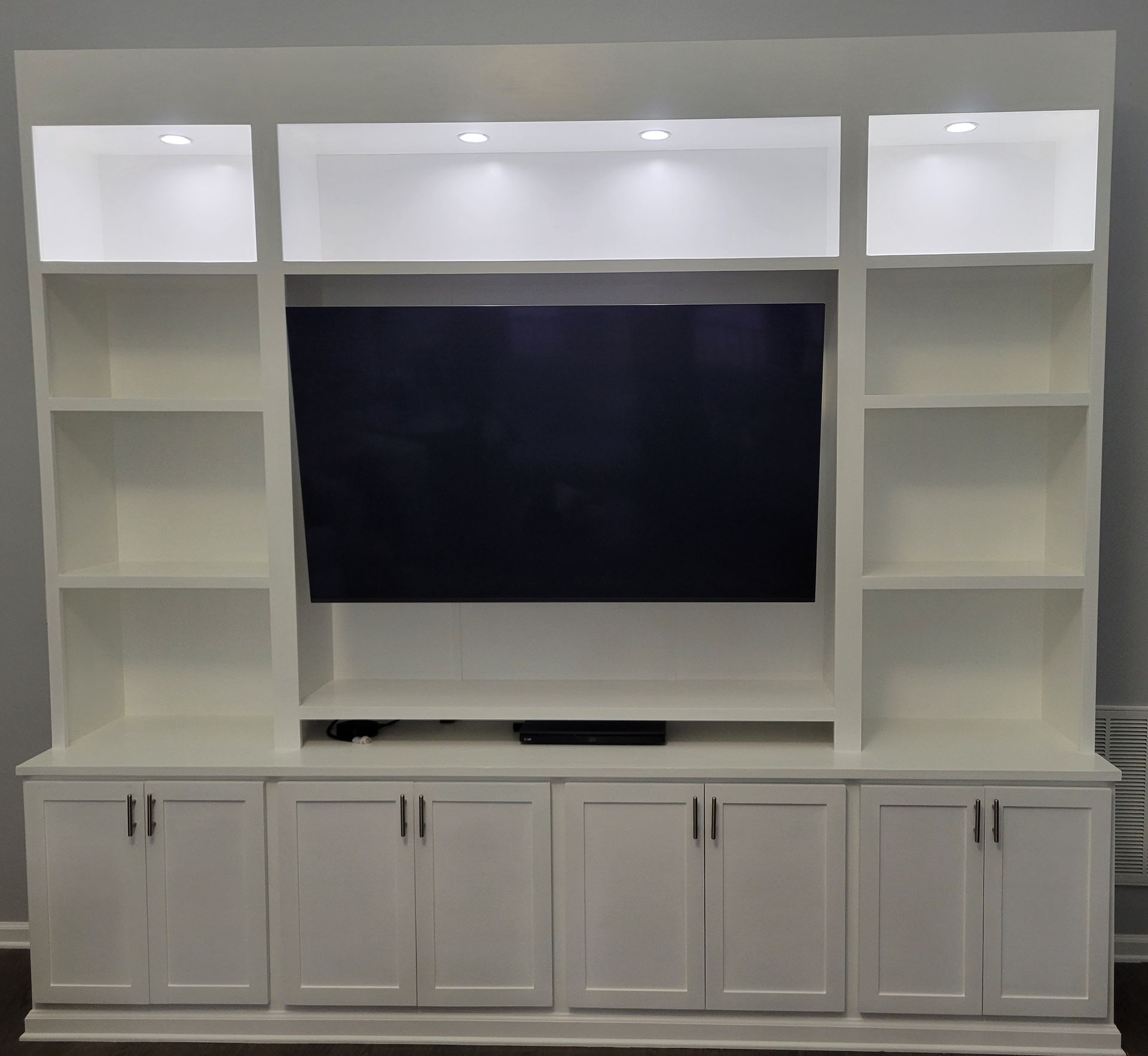 A white entertainment center with a flat screen tv and shelves.