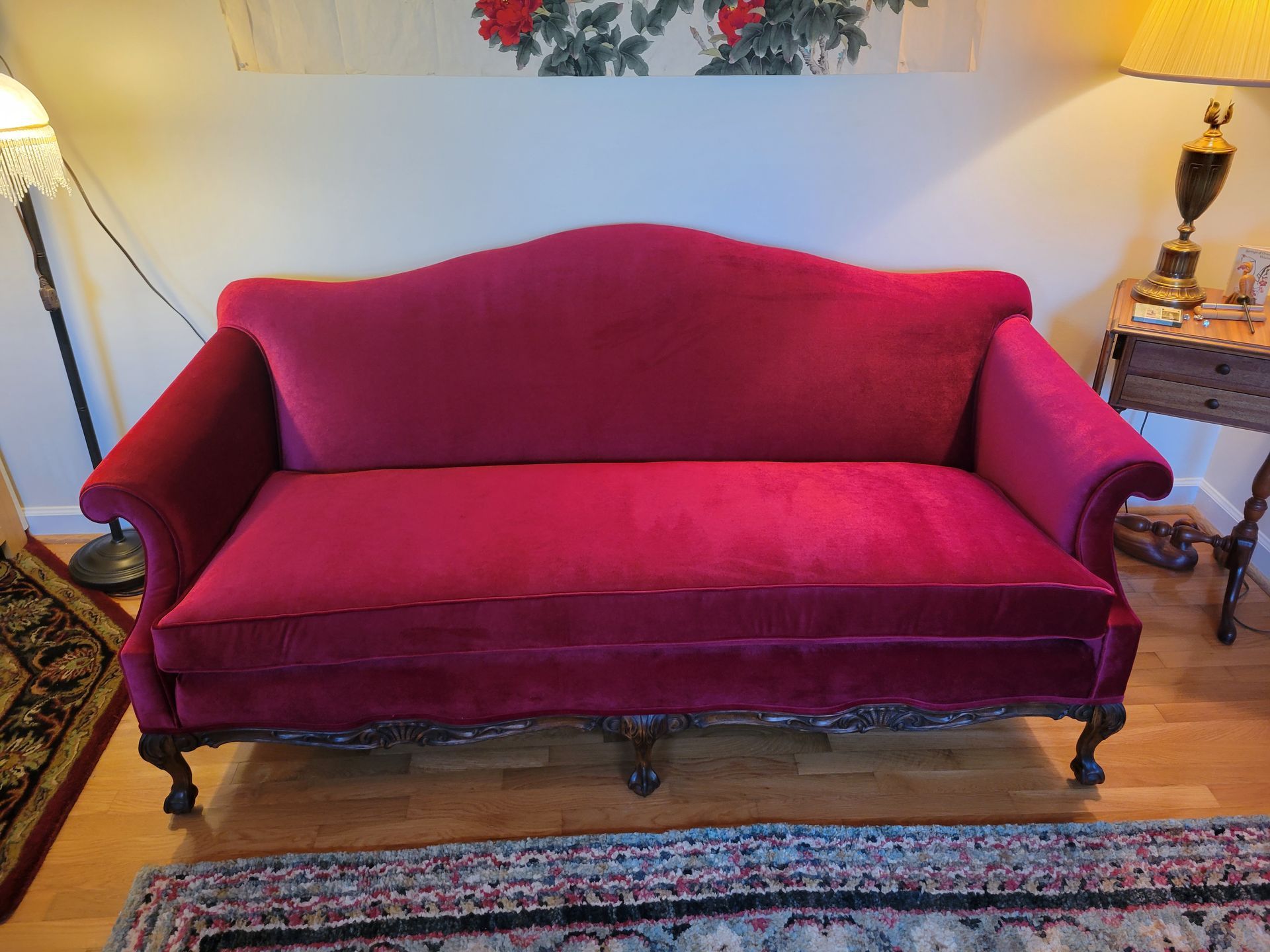 A red couch is sitting in a living room next to a rug.