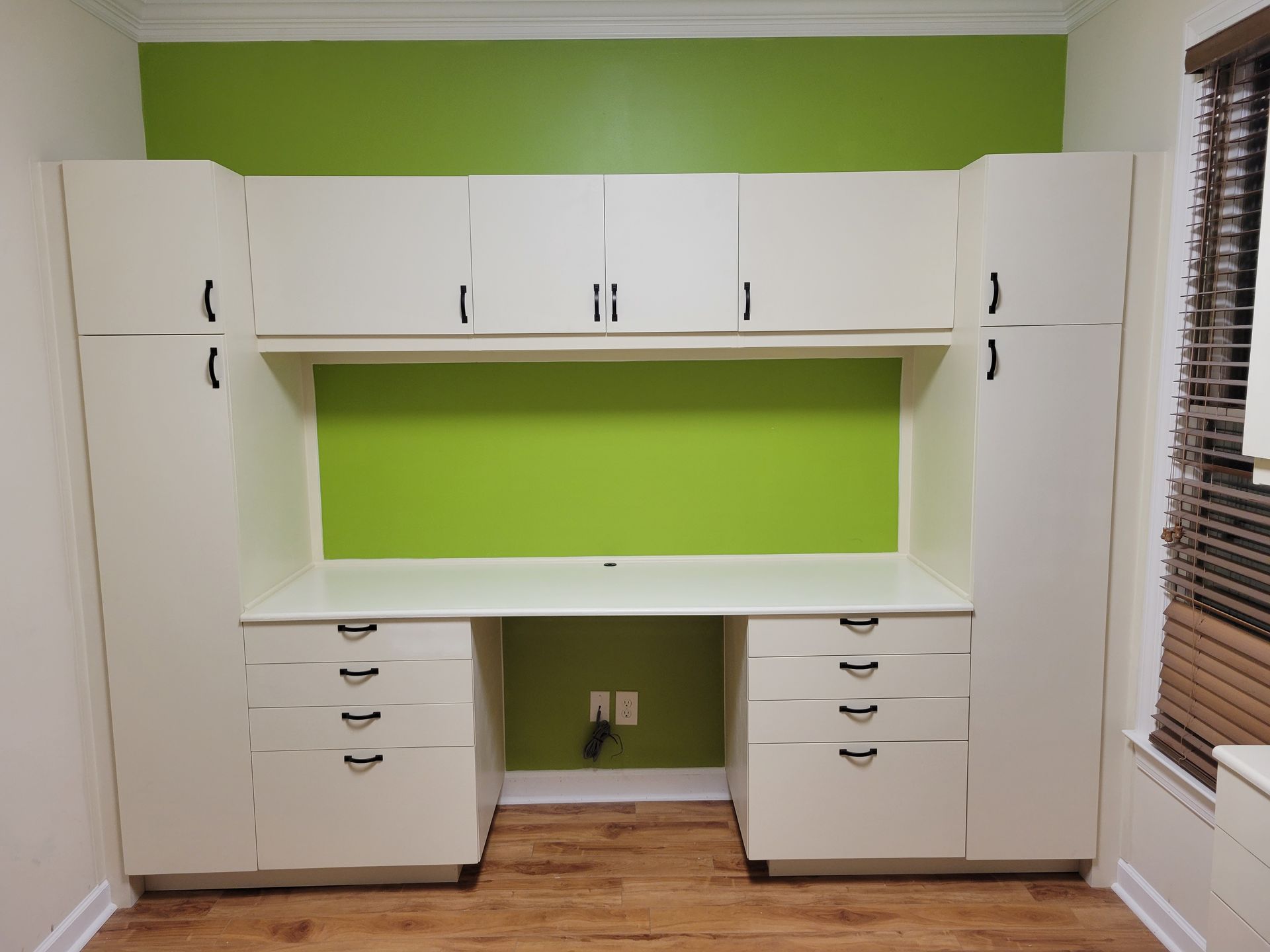 A room with a green wall and white cabinets
