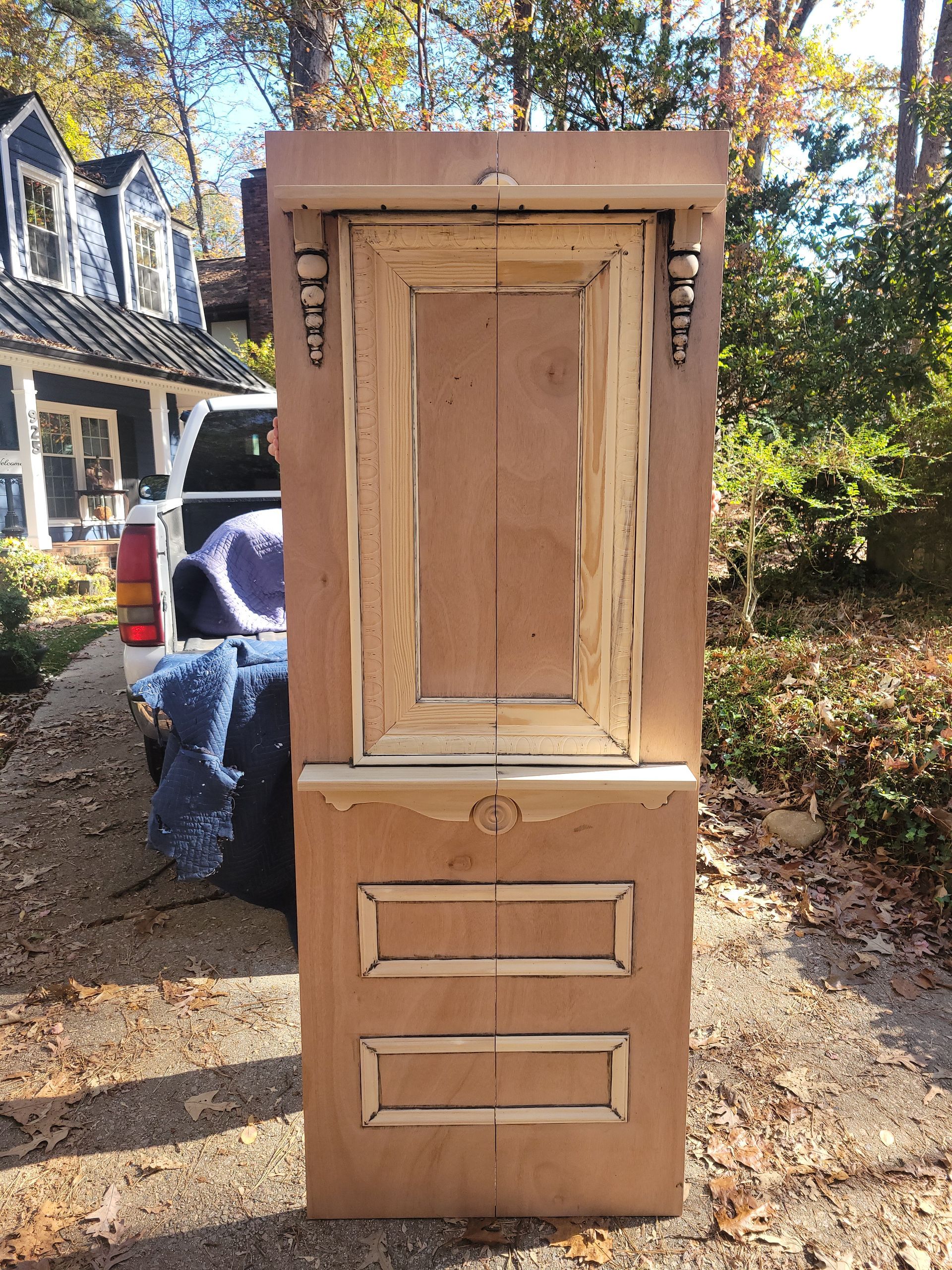 A wooden door is sitting on the side of the road in front of a house.