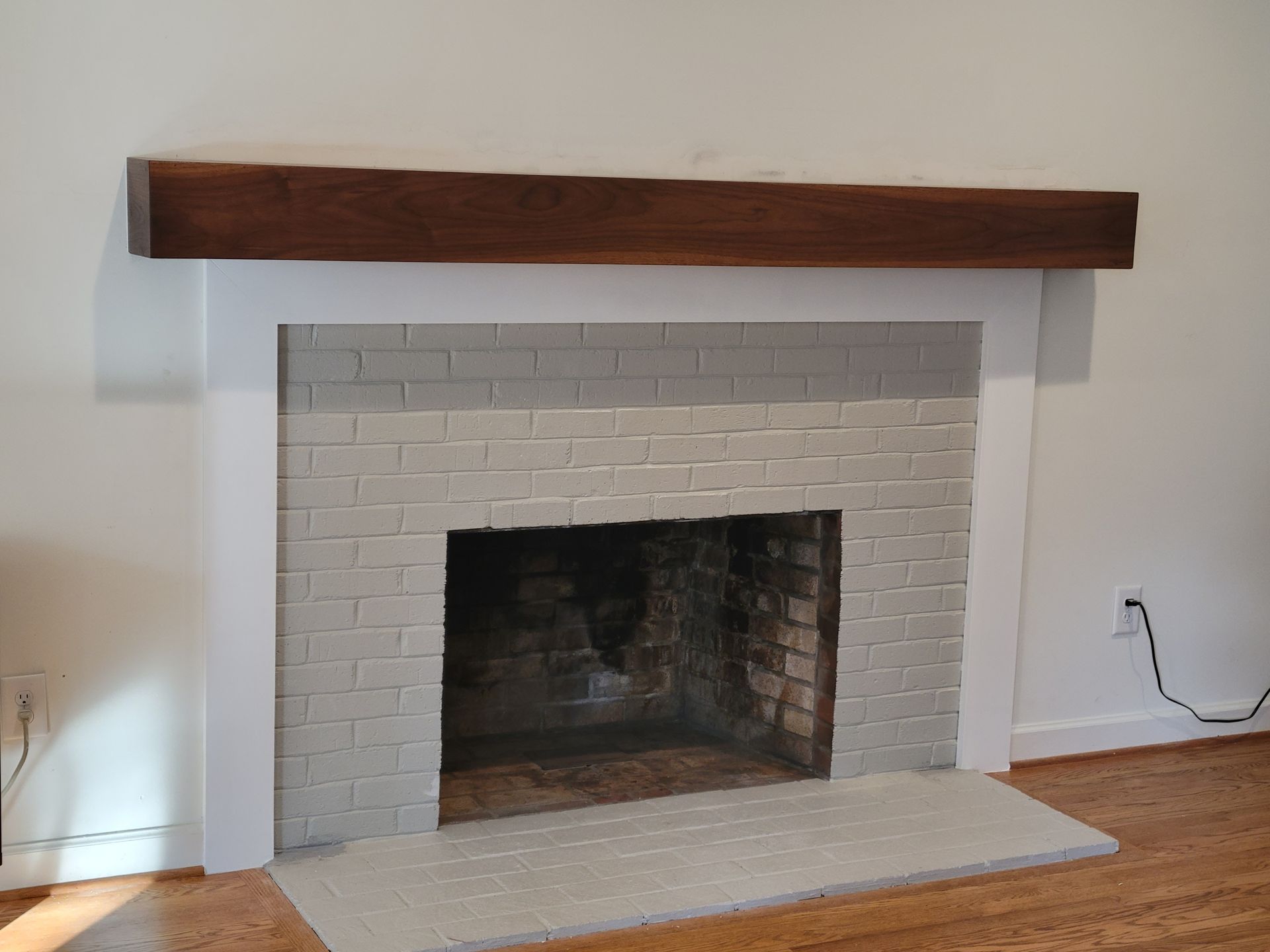 A white brick fireplace with a wooden mantle in a living room