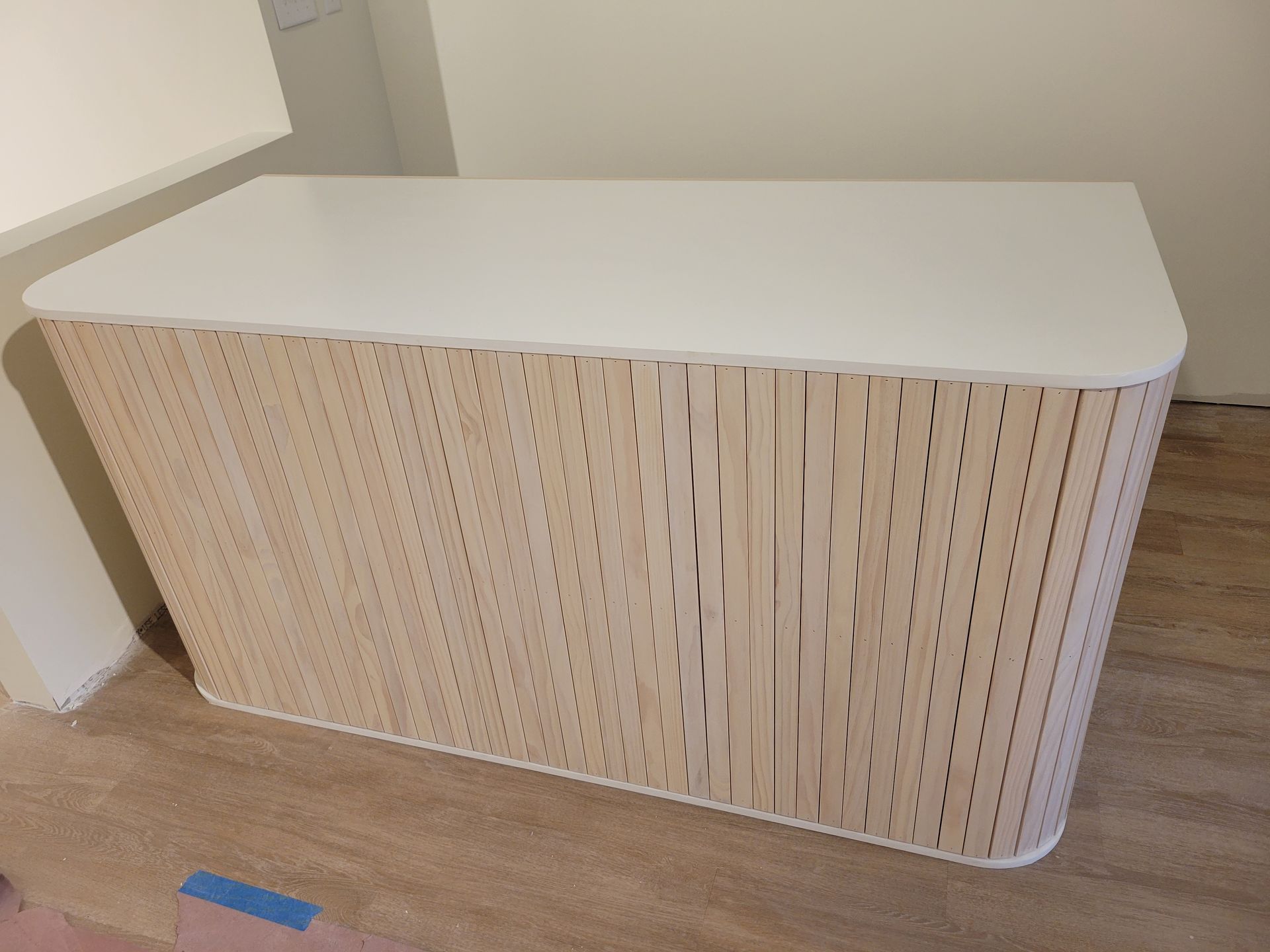 A wooden table with a white top is sitting on a wooden floor.