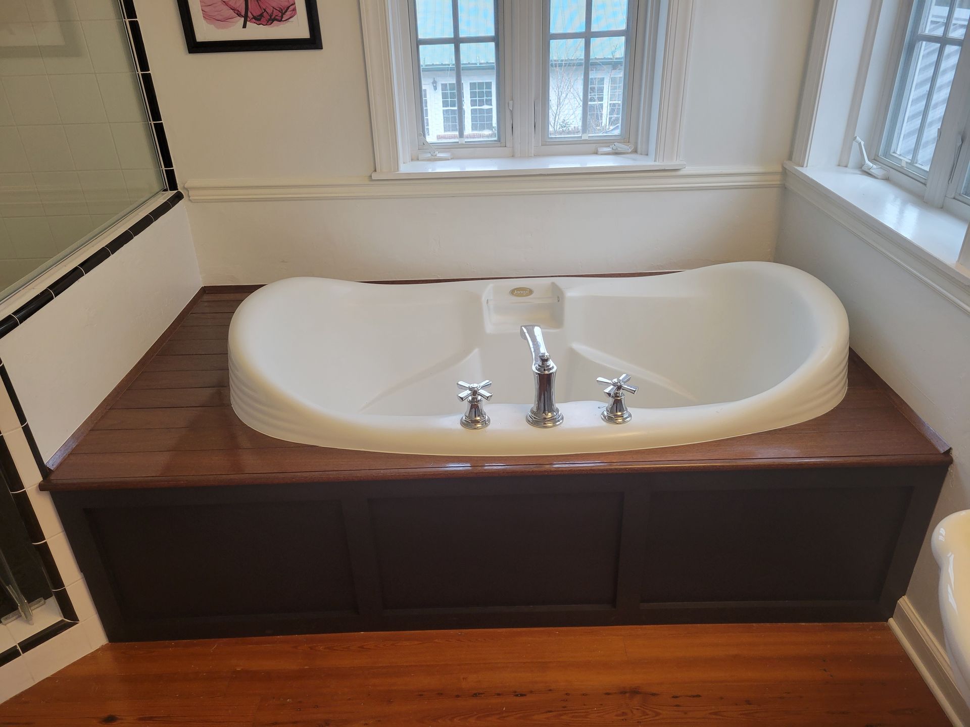 A bathtub is sitting on a wooden counter in a bathroom next to a window.