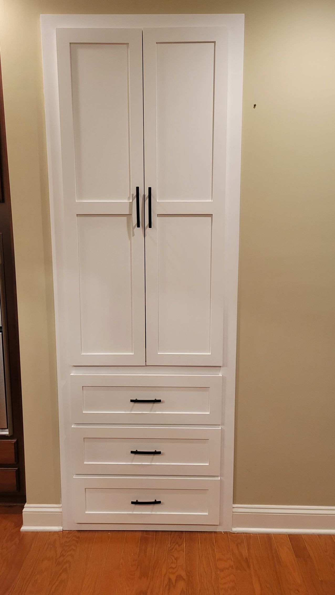 A white cabinet with three drawers and two doors in a room.