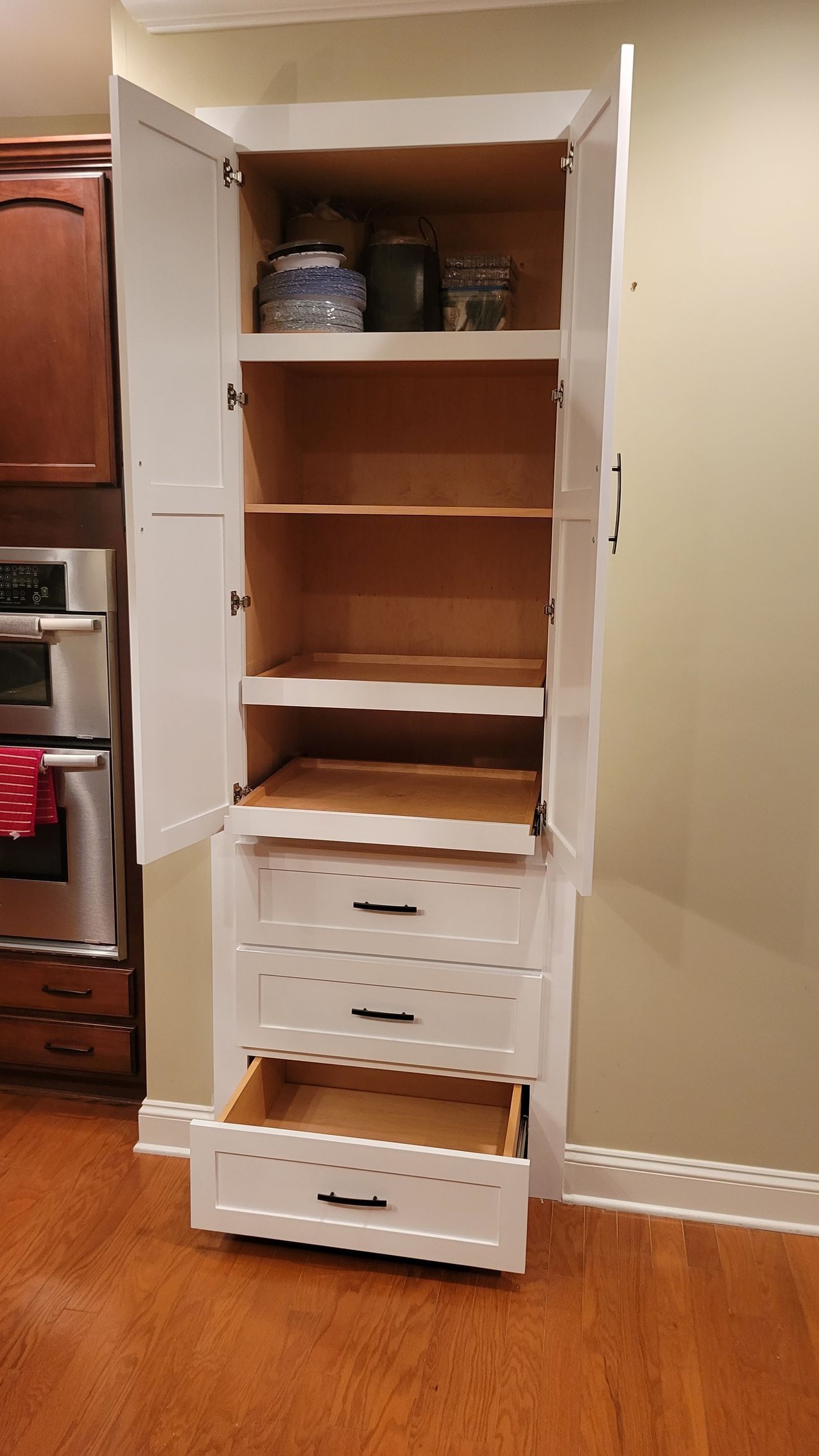 A white cabinet with drawers and shelves in a kitchen.