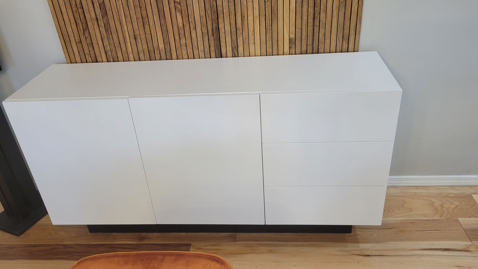 A white dresser is sitting on a wooden floor in a living room.