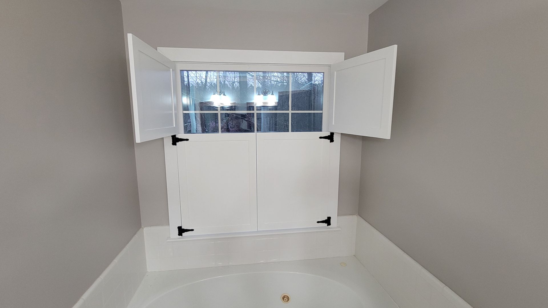 There is a window in the corner of the room with shutters open.