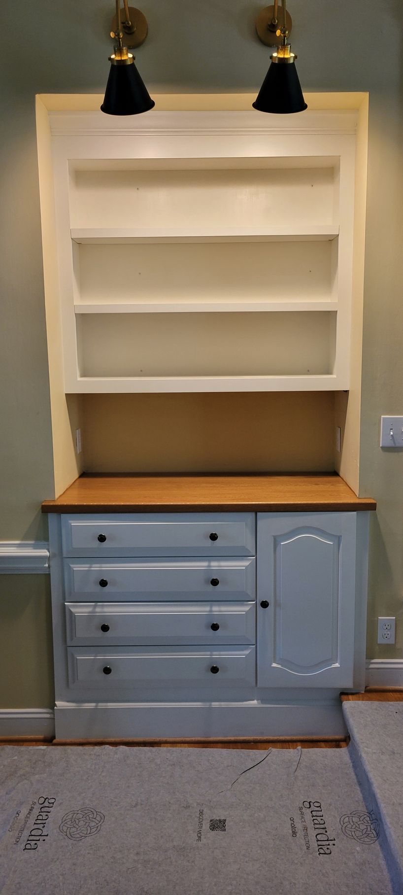 A white dresser with drawers and shelves in a room.