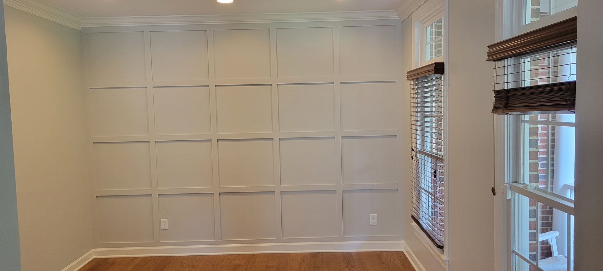 A room with a wood paneled wall and two windows.