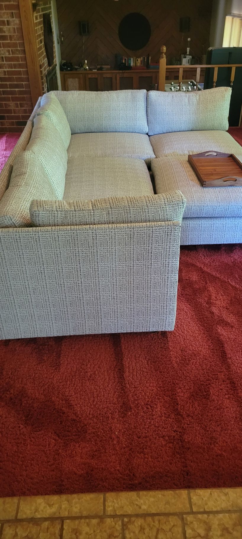 A sectional couch is sitting on top of a red rug in a living room.