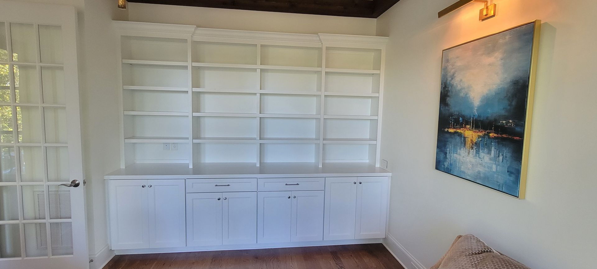 There is a painting on the wall above the shelves in the room.