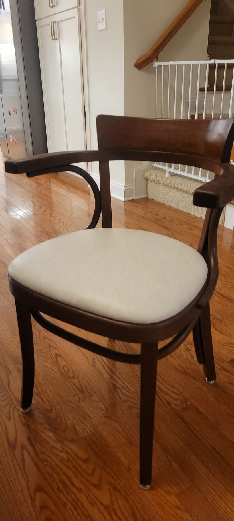 A wooden chair with a white cushion is sitting on a wooden floor in a living room.