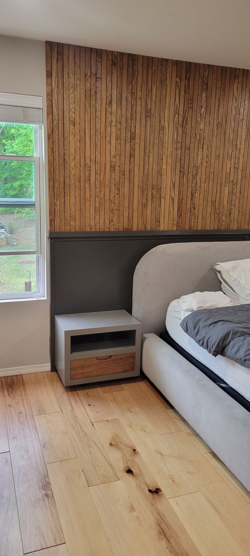 A bedroom with a bed , nightstand , and window.