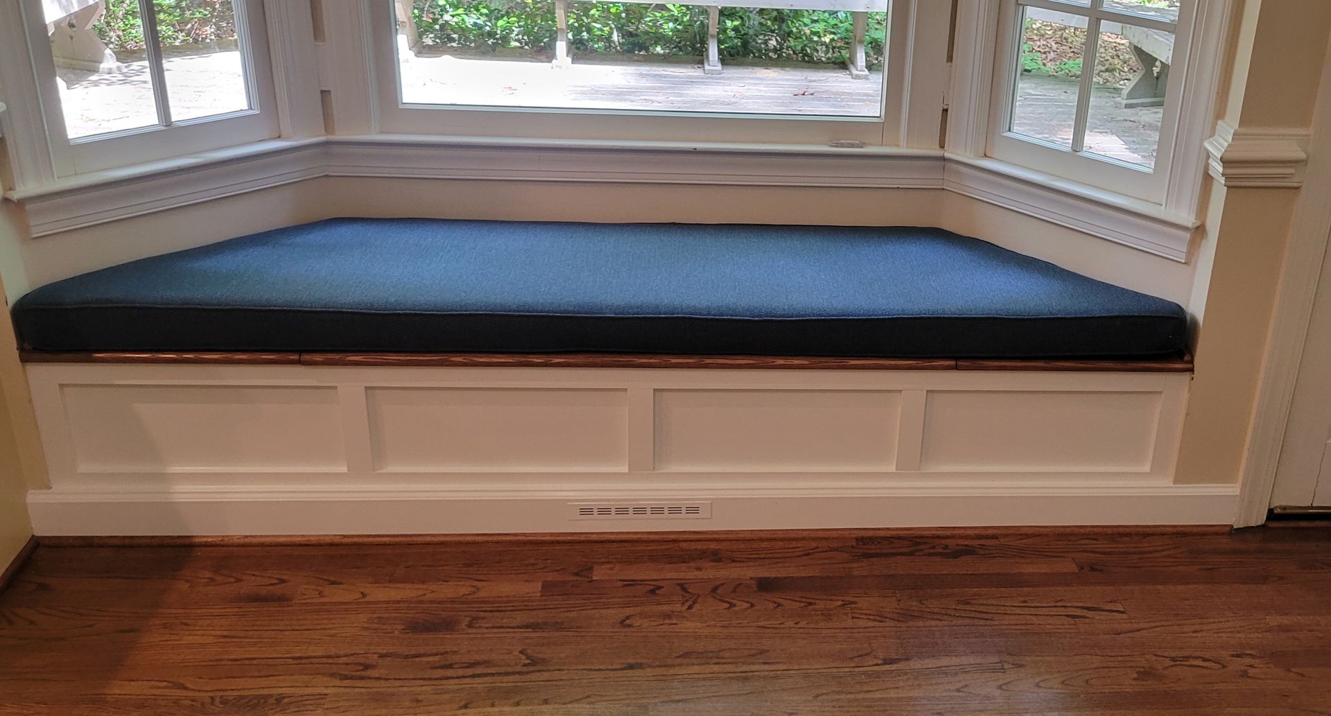 A window seat with a blue cushion in a living room.