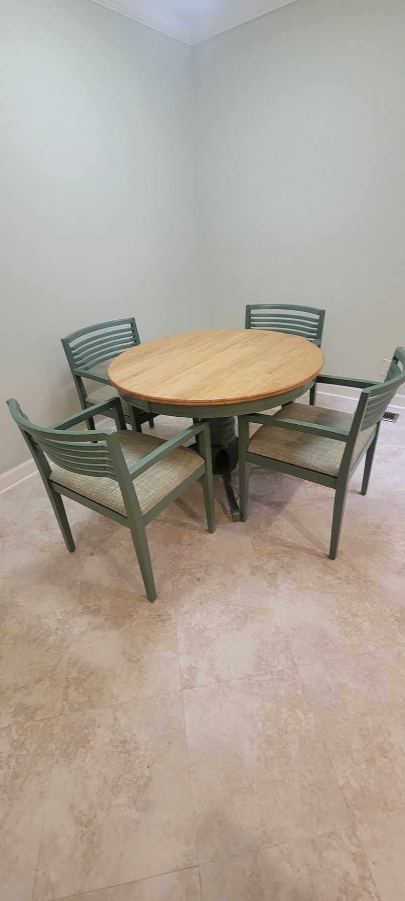 A round table with four chairs in a room.