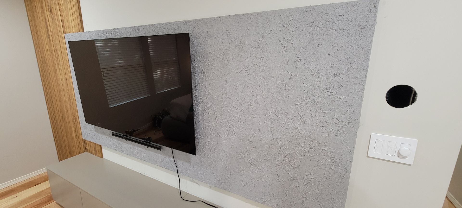 A flat screen tv is mounted on a wall in a living room.