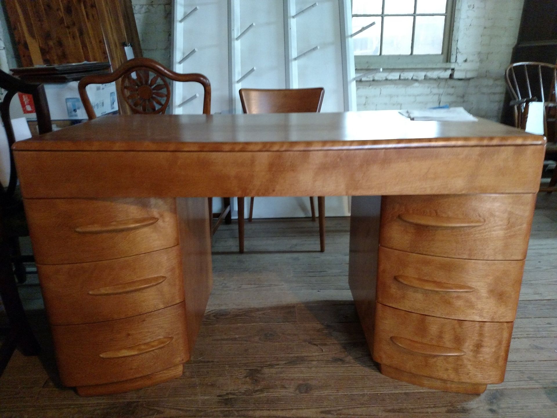 A wooden desk with drawers and a chair in a room