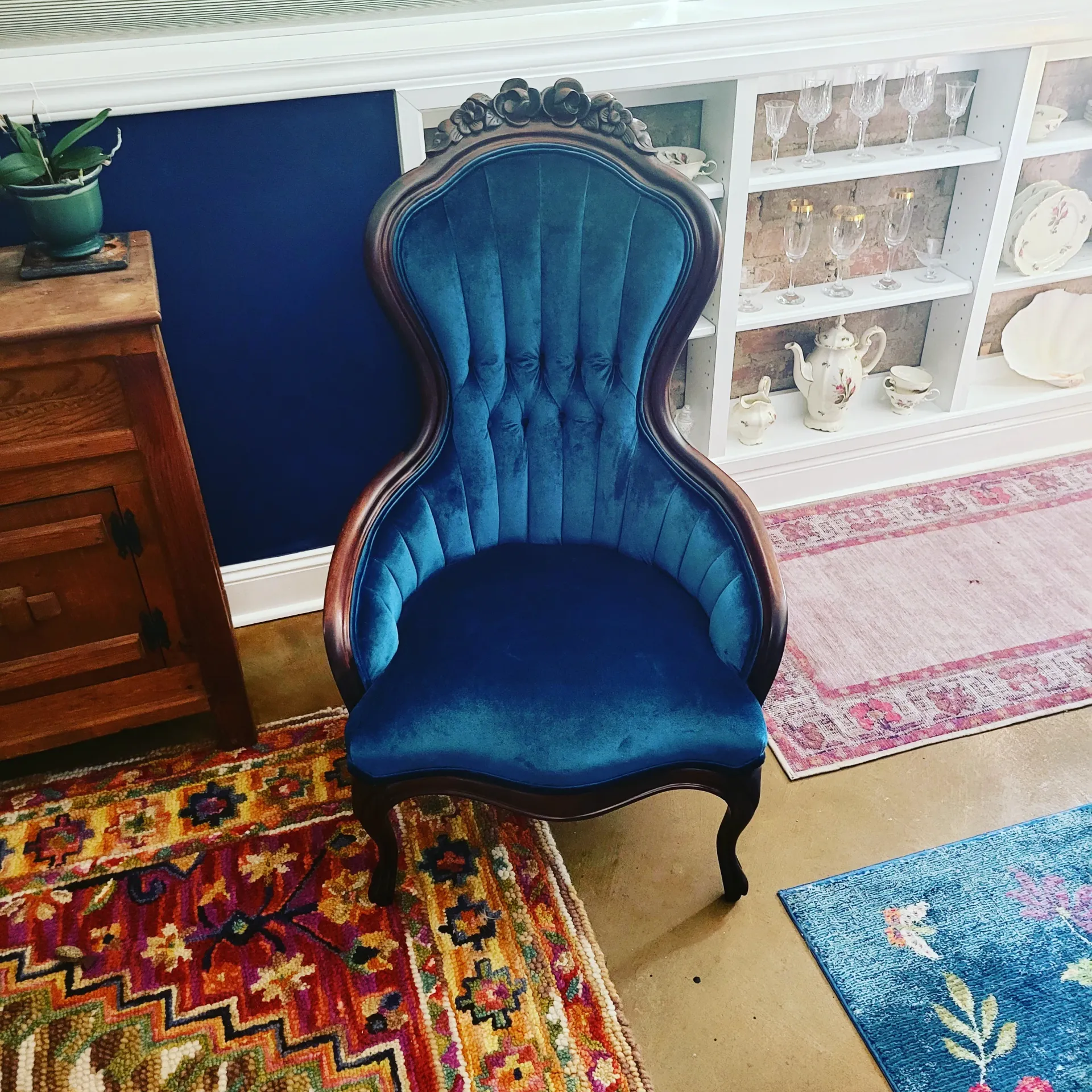 A blue chair is sitting in a living room next to a rug.